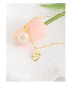 Détail d'une perle baroque avec étoile et pendentif cœur sur collier en or