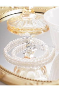 Close-up of S925 silver bow pendant and white pearls on a minimalist choker necklace