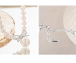 Detail view of S925 silver bow pendant and elegant white pearls on the necklace
