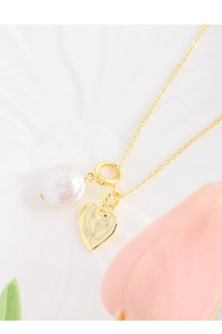 Gros plan du pendentif cœur en argent S925 et perle baroque sur collier doré