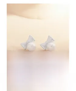 Détail de boucles d'oreilles nœud en argent S925 avec perles rondes blanches élégantes