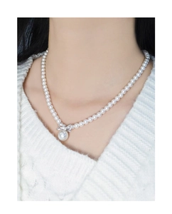 Detail of silver bow pendant and round pearl drop on a dainty beaded necklace