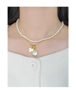 Vue détaillée d'un collier à deux rangs avec perles, cœur doré et pendentif étoile