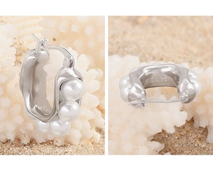 Detail of S925 silver U-shape earrings with hammered texture and round pearls