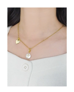 Gros plan d'un collier doré avec perle baroque, étoile scintillante et pendentif cœur