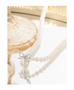 Macro shot of S925 silver bow pendant with round pearls and elegant mirror reflection