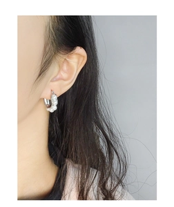 Detail of silver U-shaped pearl earrings on model showing minimalist geometric style