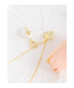 Détail macro de perle baroque avec étoile incrustée et pendentif cœur doré sur chaîne