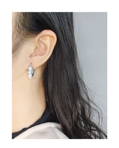 Detailed view of silver U-shaped earrings featuring three vertical white pearls on model