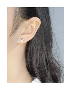 Gros plan d'une boucle d'oreille nœud et perle argentée portée par un mannequin