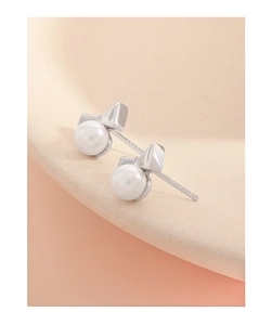 Gros plan de boucles d'oreilles nœud en argent S925 avec perles blanches sur un plateau