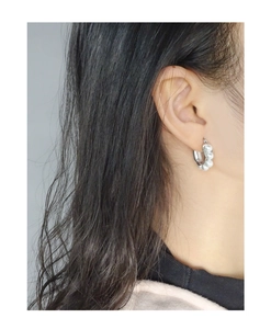 Detail of silver U-shaped hoop earring with linear pearl inlay on female model