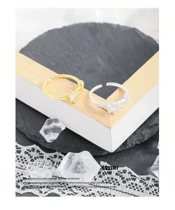 Detail of S925 sterling silver knot rings with zircons in gold and silver finish
