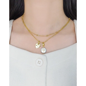 Collier cœur en perle baroque dorée avec pendentif étoile porté par un mannequin