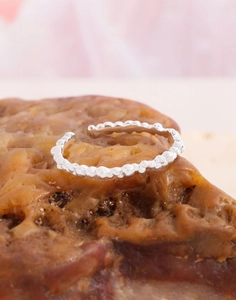 Macro shot of silver beaded open ring on a textured rock showing high polished metal texture