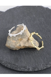 Macro shot of silver and gold S925 crown rings with zircon stones on natural rock base