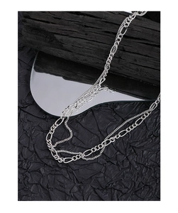 Close-up of double layered silver Figaro and flat chains on black textured paper