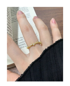 Close-up of a slim gold S925 silver ring with five sparkling zircons on an open wavy band