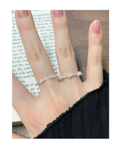Detail of silver geometric S925 ring with zircon accents worn against book background