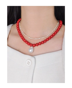 Detail einer zweilagigen Kette mit roten Perlen und einem weißen Tropfenperlen-Anhänger