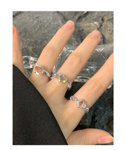 Detail of three S925 silver rings set with iridescent aurora zircons on human hand