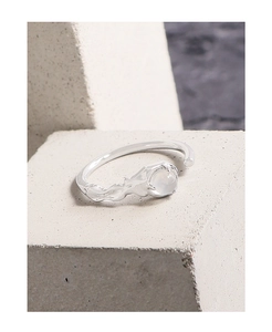 Detailed close-up of textured S925 silver ring with a round white agate stone on gray stone