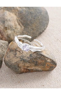 Détail macro d'une bague argentée à texture plissée avec pierre de zircon violette