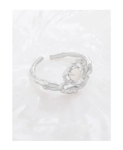 Macro detail of irregular S925 silver heart ring with pink bead on wrinkled fabric