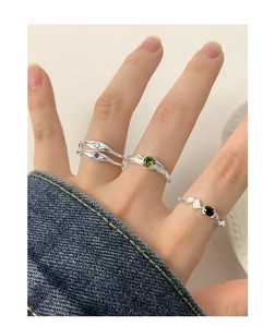 Detail of four S925 silver rings with colorful zircons and lava texture on a hand