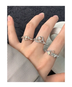 Detail showing irregular liquid metal rings with opal stones on a model's hand