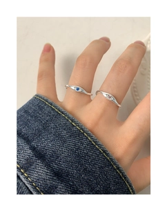 Detail of silver rings with eye-shaped design and blue and pink zircon stones on model's hand
