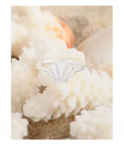 Macro shot of S925 sterling silver seashell ring on beach sand with coral