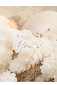 Macro shot of S925 sterling silver seashell ring resting on white coral and beach sand