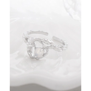 Irregular silver lava style heart ring with opal stone on a white ceramic tray