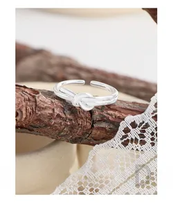 Detailed view of S925 sterling silver heart knot ring on a natural wood surface