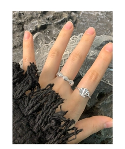 Stackable S925 silver rings with seashell and conch motifs on vintage rock background