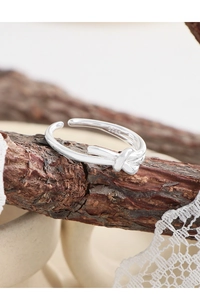Macro view of S925 sterling silver knot ring showing the material hallmark on wooden branch