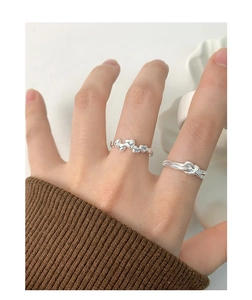 Detail of silver S925 heart-shaped and knotted rope rings worn on female fingers