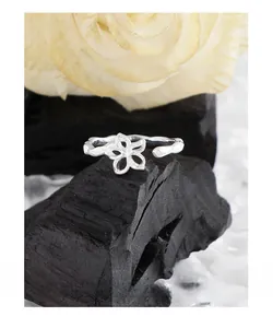 Macro shot of hollow flower ring with hammered texture on charcoal and white rose