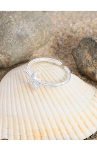 Close-up of S925 sterling silver starfish ring on white seashell and beach background