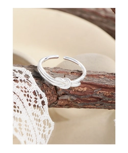 Detail of silver S925 heart knot ring with S925 hallmark on wood and lace