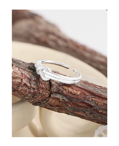 Detailed macro view of silver heart knot ring on dark wood branch texture