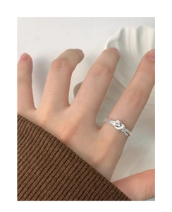 Close-up of a silver knot ring worn on a hand, highlighting its minimalist design