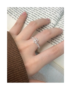 Detail of silver hollow flower ring worn by a model against a vintage book background