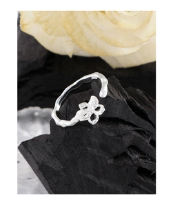Detail of silver hollow flower ring with hammered texture on black charcoal background