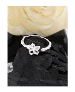 Macro detail of silver hollow flower ring with textured band on charcoal background