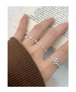 Close-up of S925 silver open flower ring and heart chain ring on a cozy book background