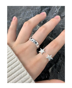 Close-up of S925 sterling silver rings with star and moon graffiti on a stone background