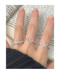 Close-up of S925 sterling silver set featuring hollow heart and floral rings on hand