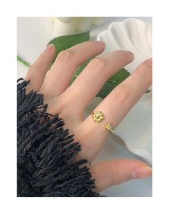 Top view of a gold daisy flower open ring worn on a finger for an elegant style